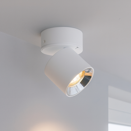 White ceiling light fixture on a neutral wall with a window in the background