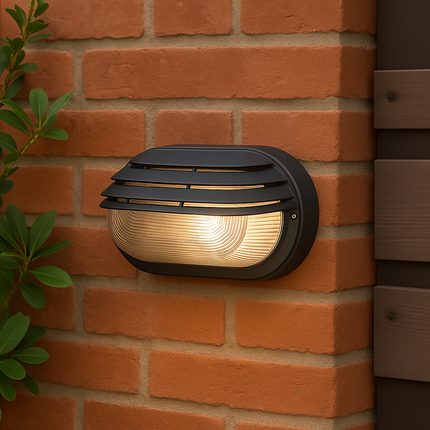 Black outdoor wall light fixture on a brick wall with a plant to the left.
