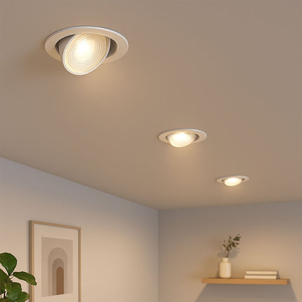Three recessed ceiling lights in a room with a plant and shelf.