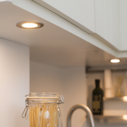 Under-cabinet lighting in a kitchen with a jar of pasta.